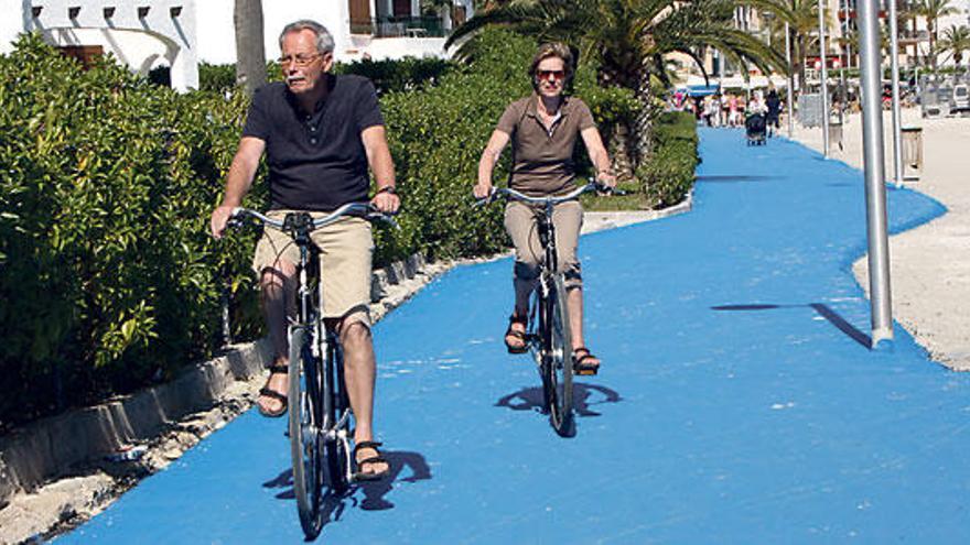 Dos personas circulan en bicicleta sobre el asfalto azul.