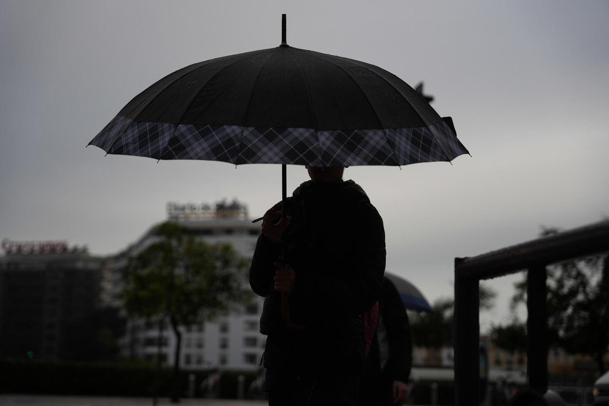 Archivo - Peatones se protegen de la lluvia bajo sus paraguas