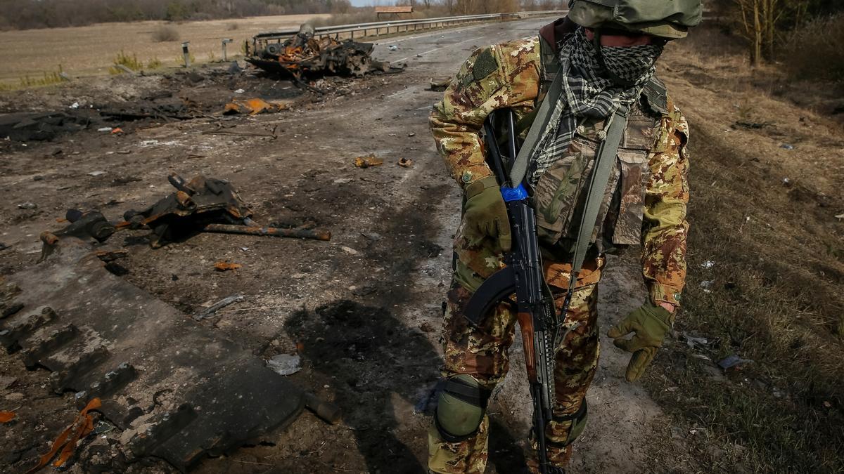 A Ukrainian serviceman stands near the wreck of a Russian tank on the front line in the Kyiv region