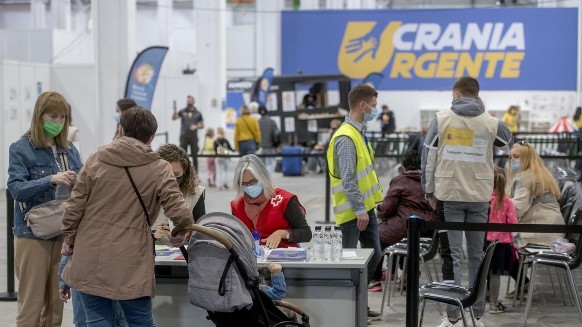 Familias procedentes de Ucrania cumplen con los trámites burocráticos ayudados por personal de la Cruz Roja en la Fira de Barcelona.