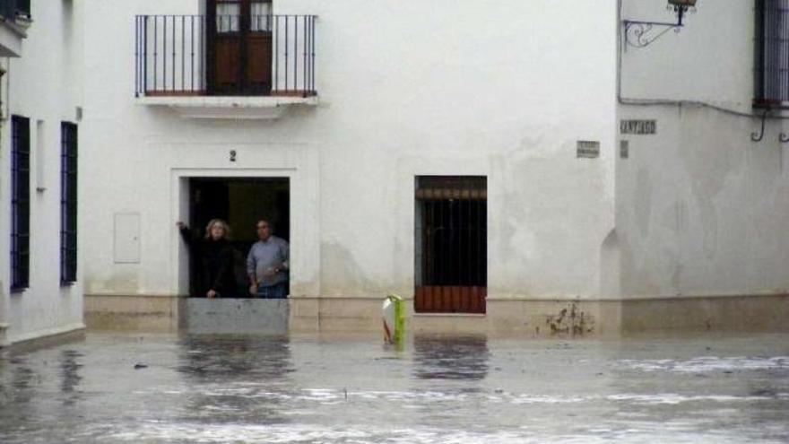 Dos vecinos observan parapetados en sus casas las calles inundadas de Écija. / efe