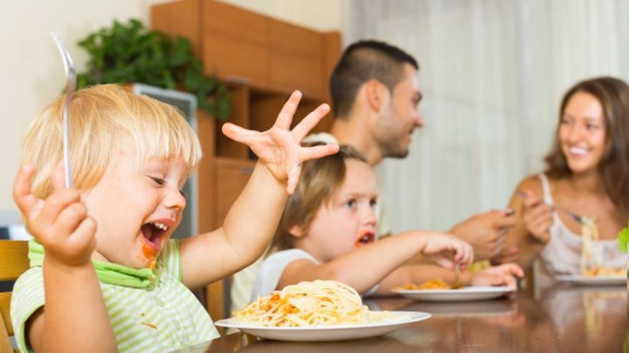 Padres y niños comiendo spagueti.