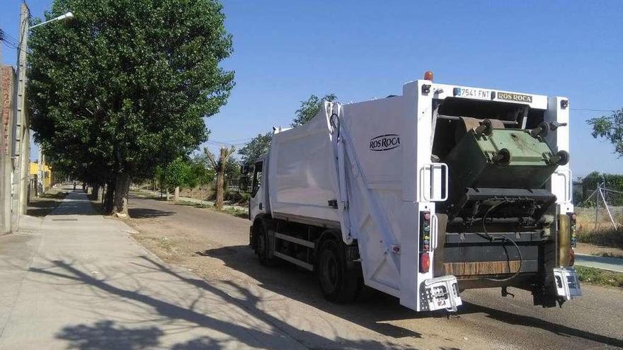 Un camión recoge uno de los contenedores de basura situado en el camino del cementerio.