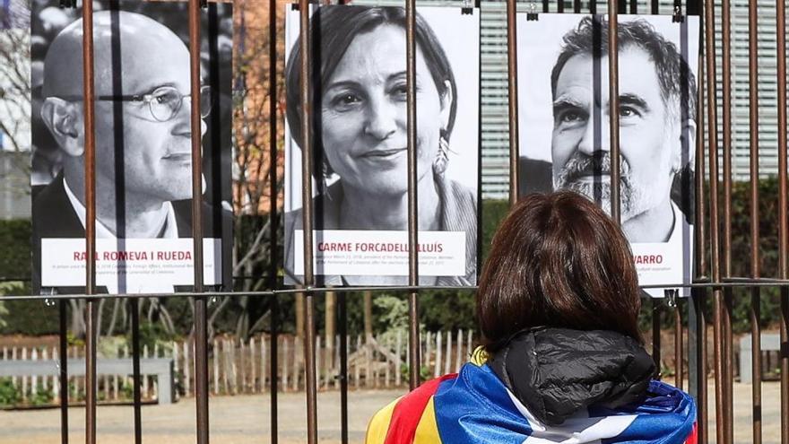 Una noia amb una estelada, davant de cartells de Forcadell, Romeva i Cuixart.