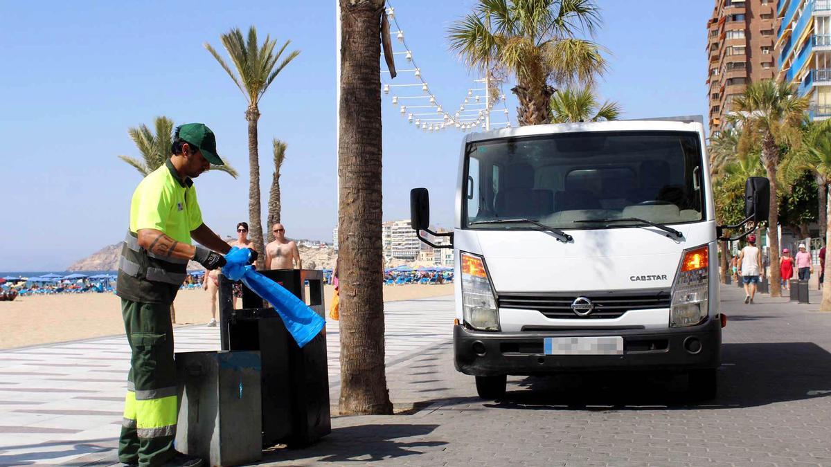 Un operario vacía una papelera en la playa de Levante de Benidorm.