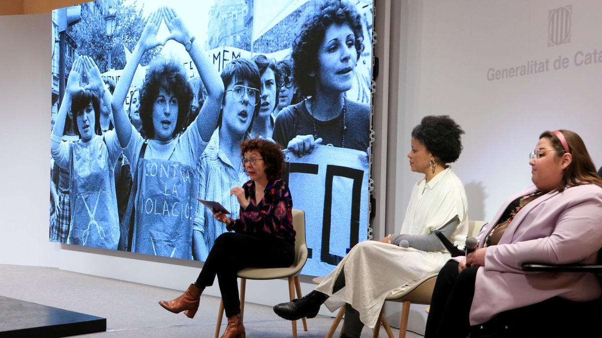 La periodista Montse Virgili modera un diálogo entre la dramaturga Denise Duncan y la activista anticapacitista Oyirum, con una de las fotografías icónicas de Pilar Aymerich, en el acto institucional del 8-M en el Palau de la Generalitat