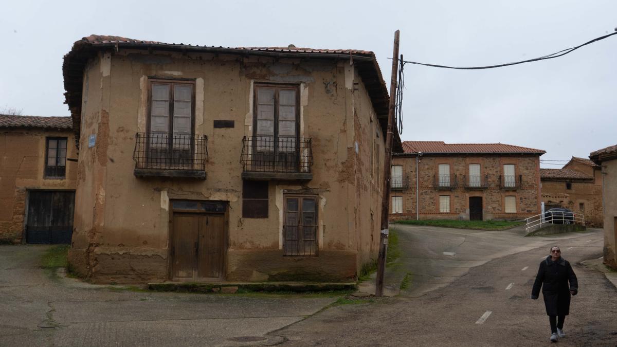 Una mujer camina por un pueblo de Zamora, al lado de una casa en ruinas