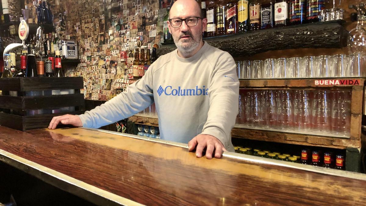 Francisco Ventura, dueño del local, posa en la barra. Detrás miles de fotografías de clientes.