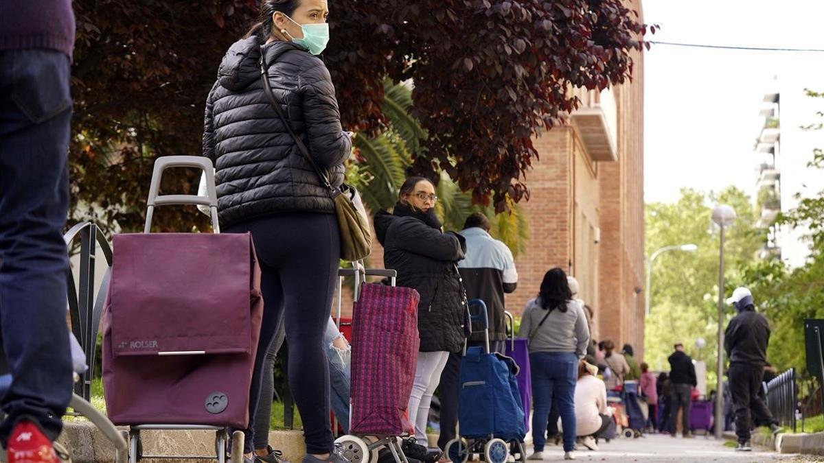 Cola de personas que esperan para recoger los alimentos que distribuye entre los más necesitados la organización Madrina en Madrid, el 28 de abril