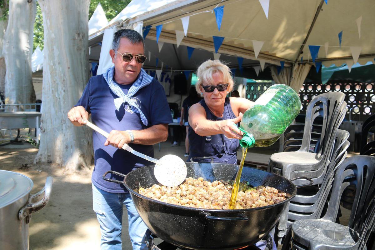 Dos peñistas preparan caracoles a la gormanta