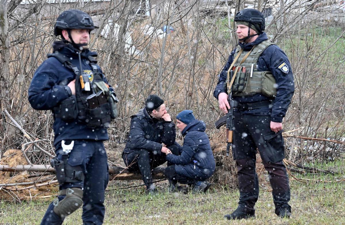 Ciudadanos de Bucha lloran mientras se reúnen cerca de una fosa común tras la matanza del ejercito ruso en su localidad.