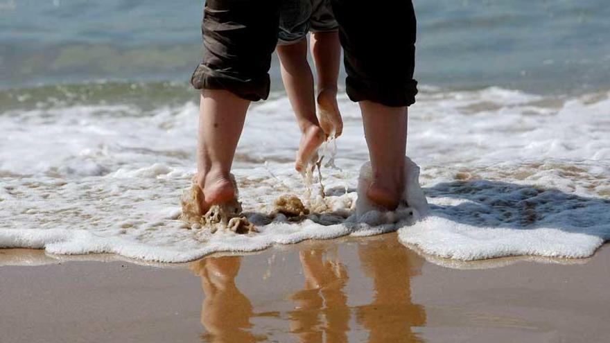 Una madre juega con su hija en la orilla de una playa.