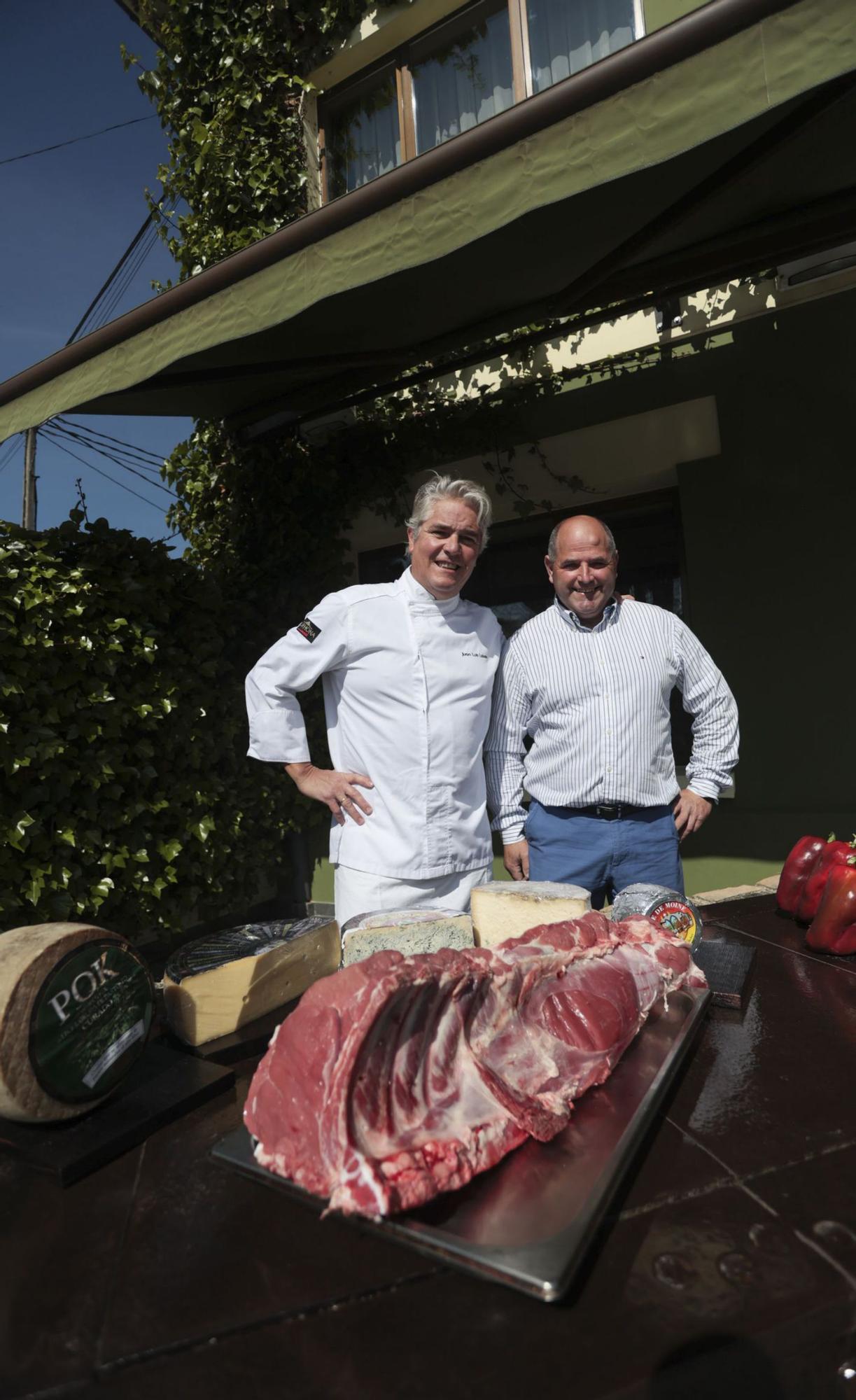 Juan Luis Lobato y Juan Carlos Aller, delante de Casa Lobato, ante la carne de las vacas que cría el ganadero en Ules. | |   IRMA COLLÍN