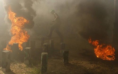 A young Palestinian jumps over fire during a military-style exercise at a summer camp organized by Hamas movement in Gaza City