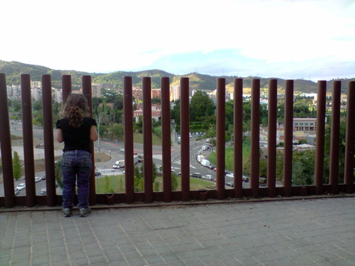 Una barana molt perillosa.La fotografia la vaig fer dilluns passat, al costat d’un parc infantil del carrer de Sant Genís, al barri del Carmel de Barcelona. Una nena treu el cap per la barana, que, en teoria, la protegeix de caure per un desnivell molt alt, però hi ha diversos barrots arrencats que deixen prou espai perquè un nen es precipiti al buit. ¿Els senyors governants podrien invertir una mica menys en propaganda i dedicar una mica de diners a la seguretat dels nostres fills?