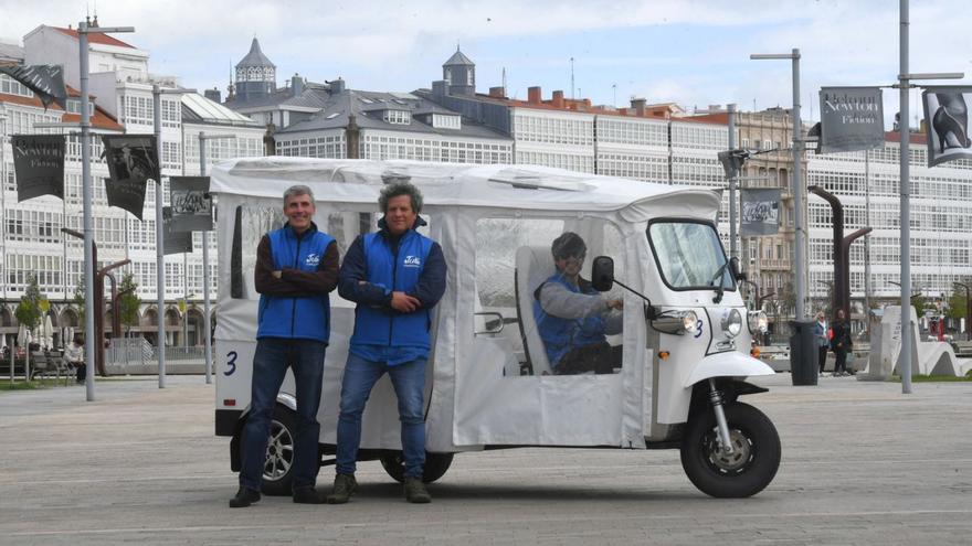 Conductores de ‘tuk tuk’ junto a uno de los vehículos, este miércoles en la Marina.