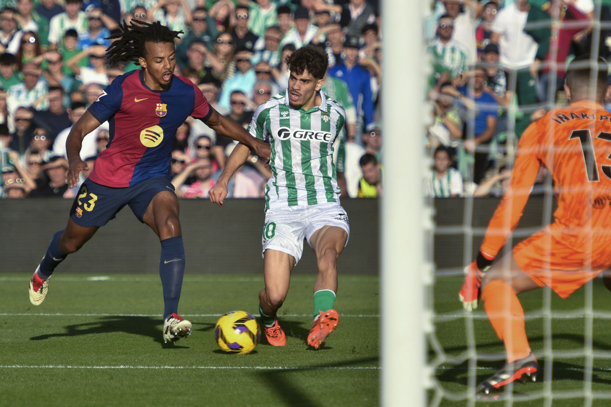 El defensa francés del FC Barcelona Jules Koundé (i) disputa un balón con el delantero hispano-marroquí del Betis Ez Abde (c) durante el partido de la jornada décimo sexta de LaLiga EA Sports que disputaron Real Betis Balompié y FC Barcelona en el Estadio Benito Villamarín de Sevilla. EFE/ Raúl Caro. (Betis) (Barcelona)