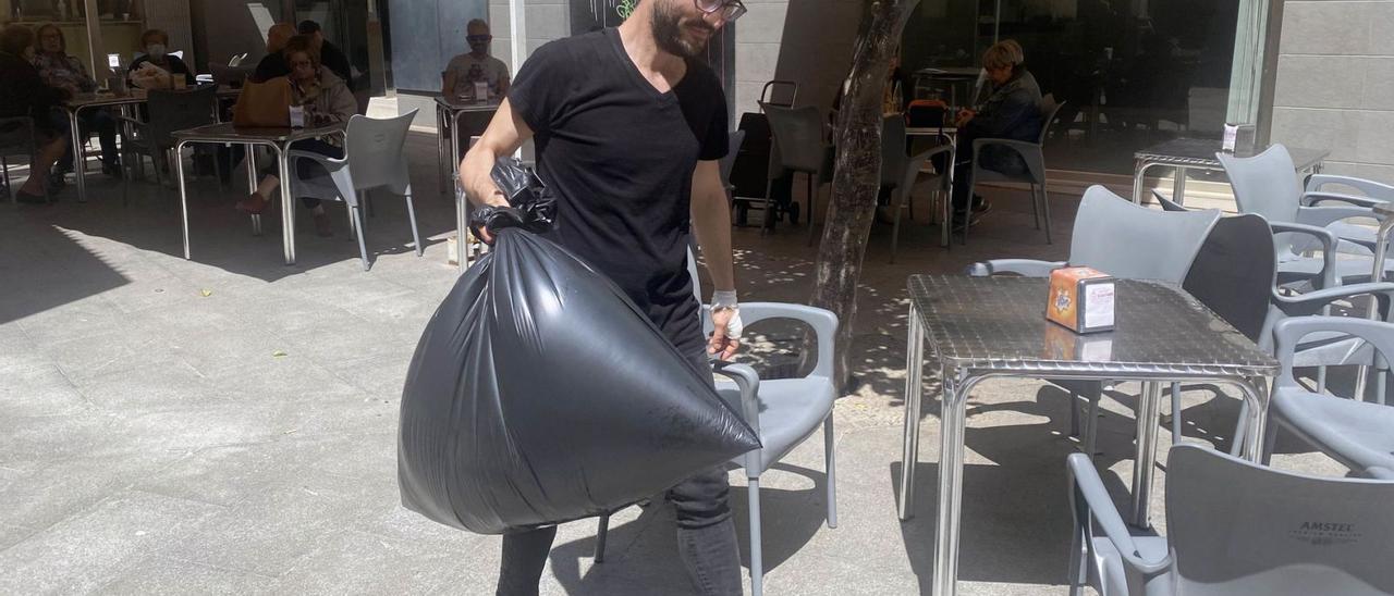 El camarero de un local del centro de Elche, con una bolsa de basura. | MATÍAS SEGARRA