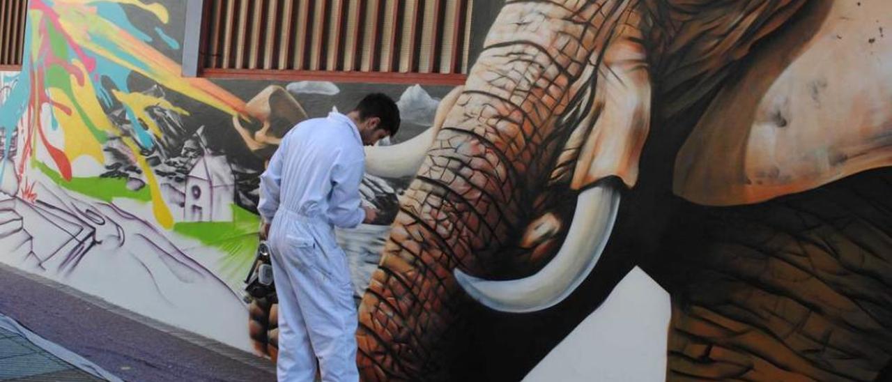 Bastián Prendes pinta el mural de la calle Celleruelo de la Pola.