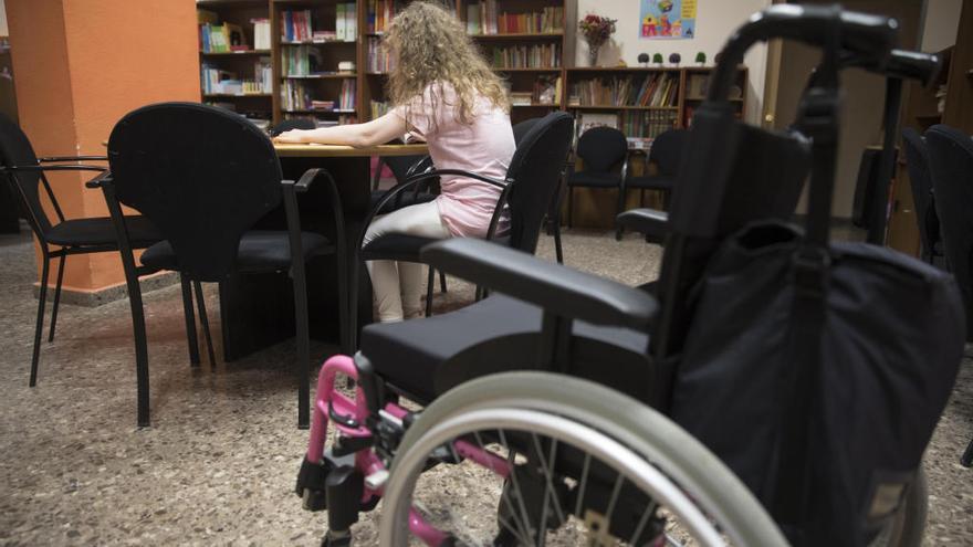 Una menor con diversidad funcional estudia junto la silla de ruedas con la que se desplaza.