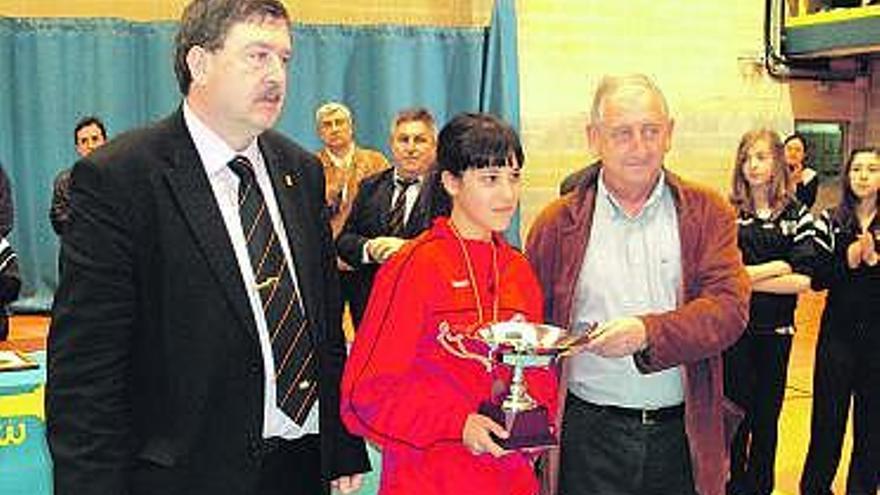 La capitana del Atarfe recibe la copa de campeonas de España flanqueada por un directivo de la Federación Española y el alcalde cangués, Alfredo García.