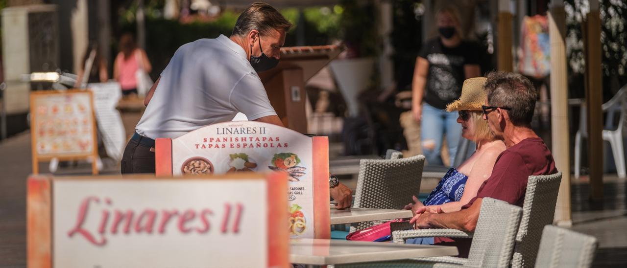 Un camarero sirve a unos turistas en una terraza.