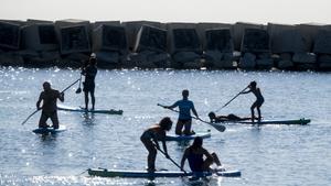 Jóvenes practicando paddle surf en la zona de baños del Fòrum