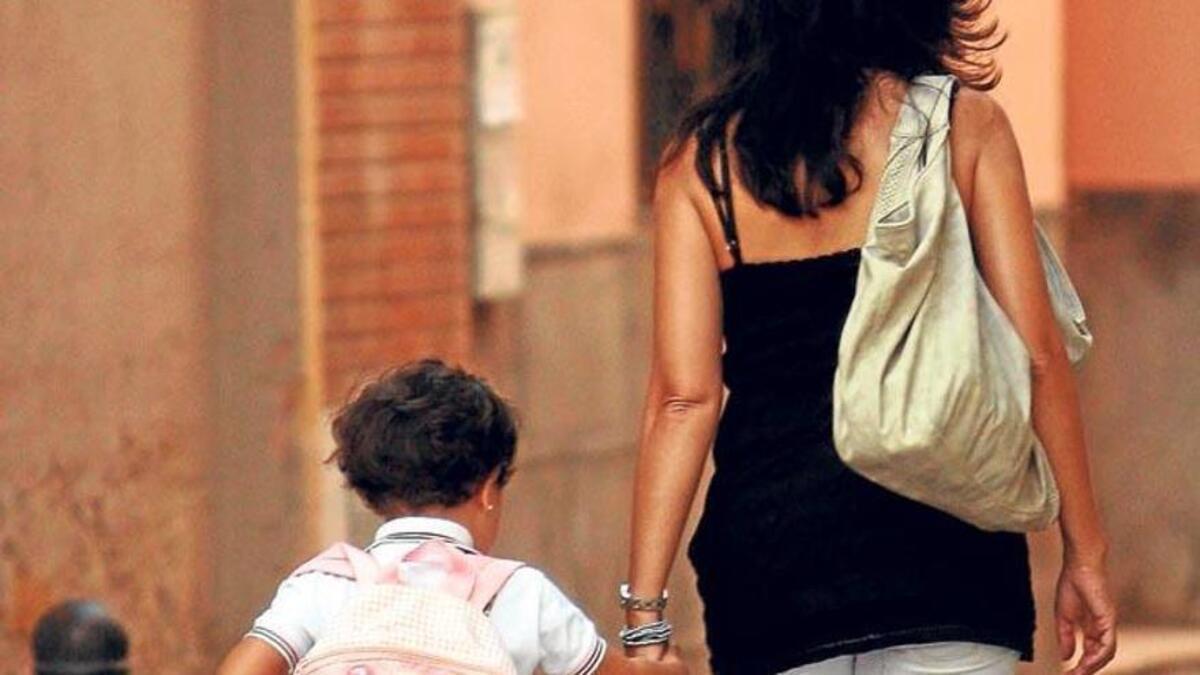Una madre con su hijo paseando por la calle.