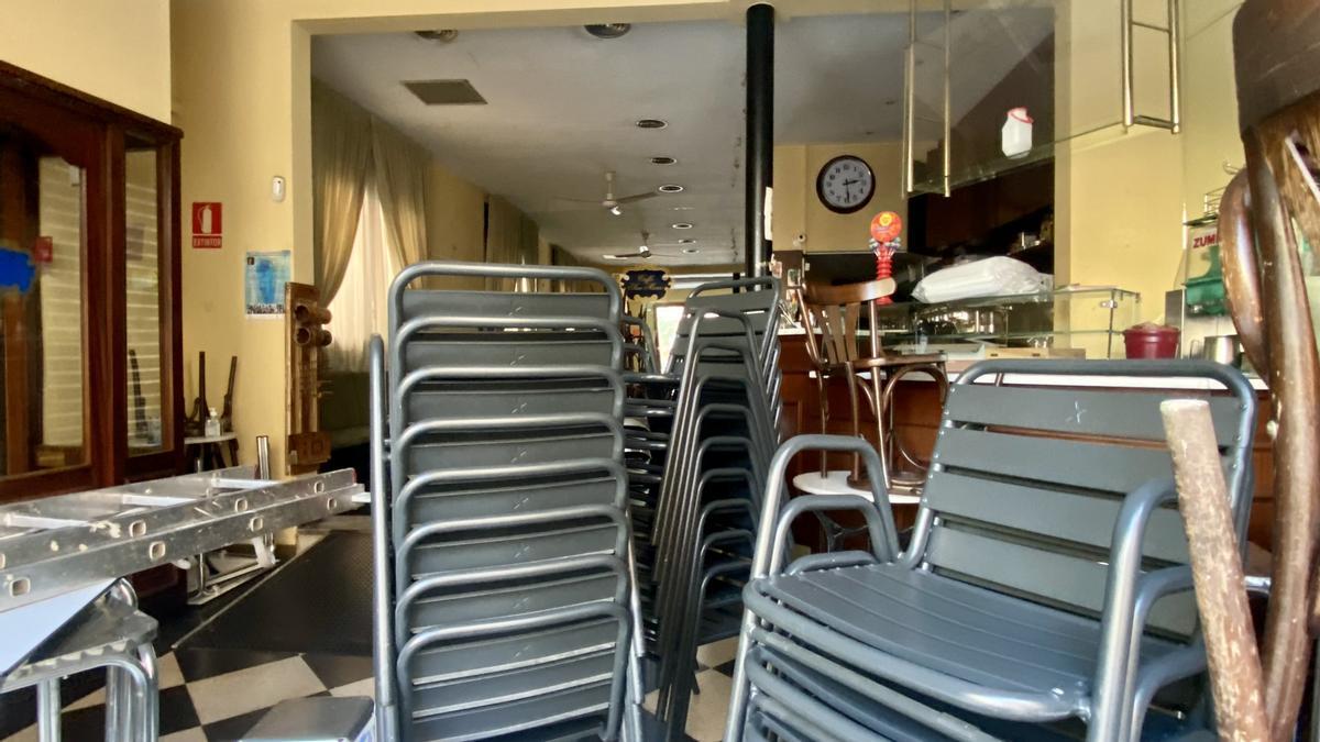 El interior del café, con las mesas apilonadas y con sillas de plástico que tienen toda la pinta de substituir a las de madera de siempre