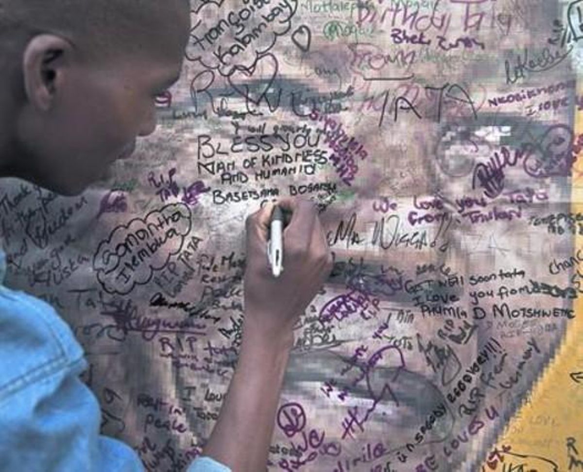 Un veí de Soweto firma un condol en un pòster als afores de la vella casa de Mandela.