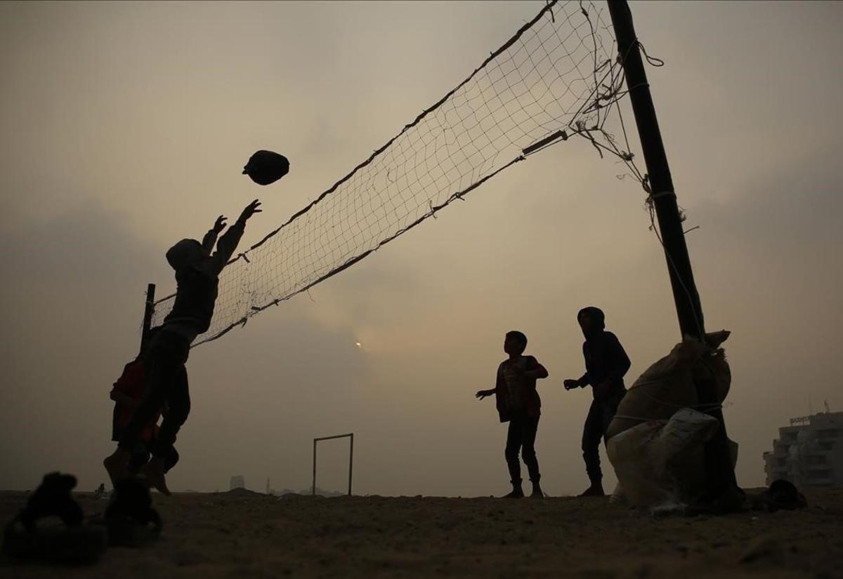 Niños palestinos juegan al voleibol con una pelota de plástico cerca de sus casas en la ciudad de Gaza.