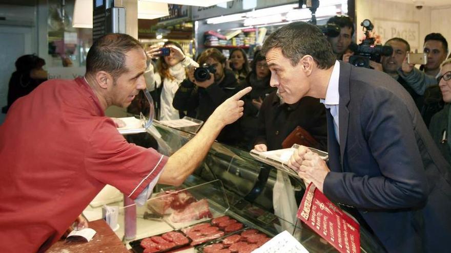 Pedro Sánchez habla con un carnicero durante su visita a Nou Barris, el distrito obrero de Barcelona.