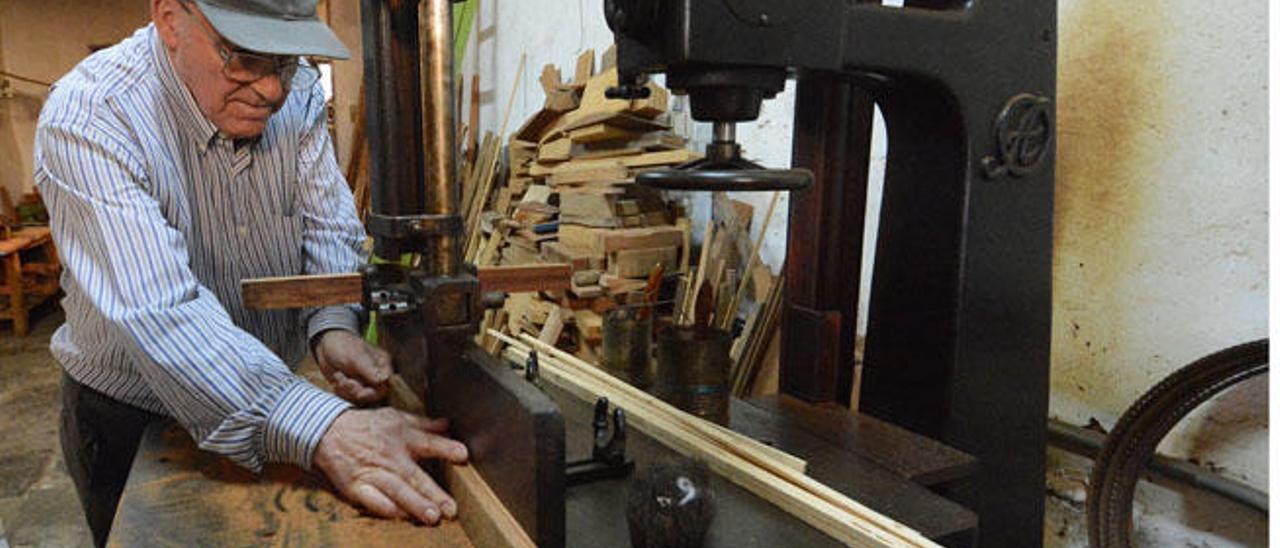 Servando Socorro muestra cómo funciona una de las máquinas que adquirió su padre en 1945 y que aún tiene en su taller de ebanistería centenario.