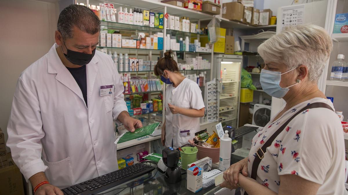 Pacientes con mascarilla en una farmacia