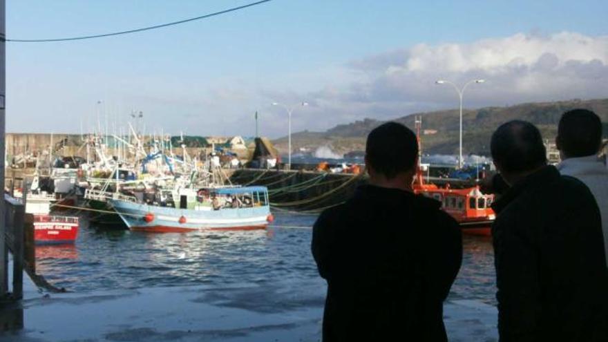 Varios marineros observan el oleaje en el puerto de Llanes durante el temporal de ayer.