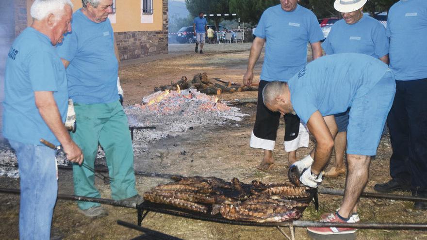 Vecinos de Villaflor preparan el asado de costillas para su reparto.