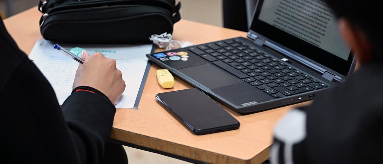 Un ordenador y un móvil encima de la mesa de un instituto catalán, este curso.