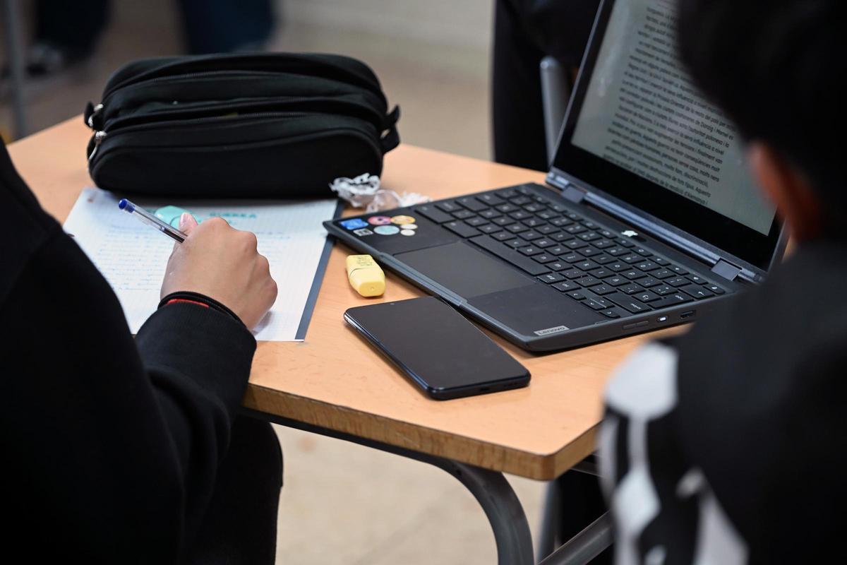 Un ordenador y un móvil encima de la mesa de un instituto catalán, este curso.
