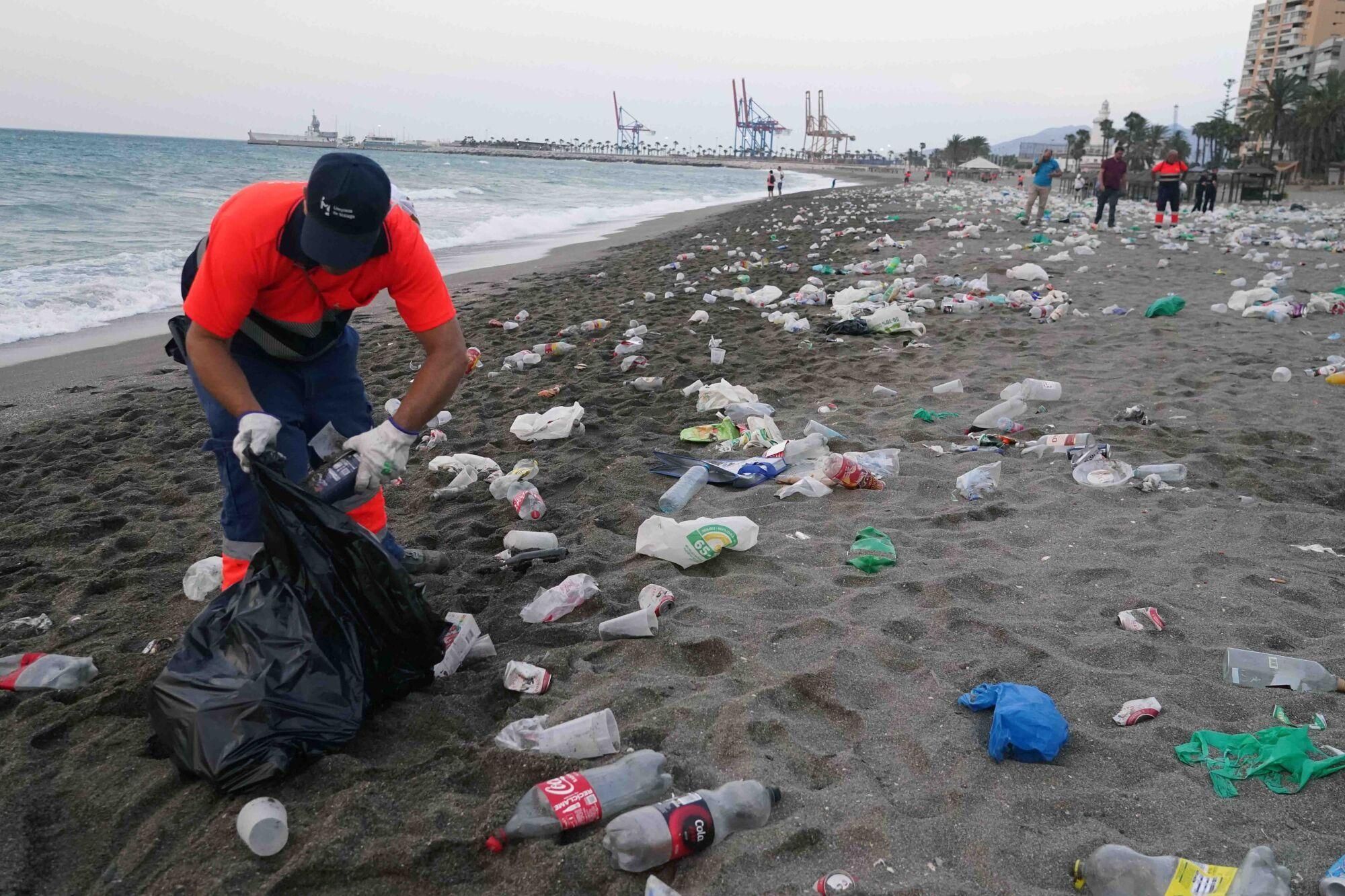 Varios operarios de la empresa de limpieza de Limasam, recogen los residuos de la playa de La Malagueta, tras la Noche de San Juan en Málaga 2025