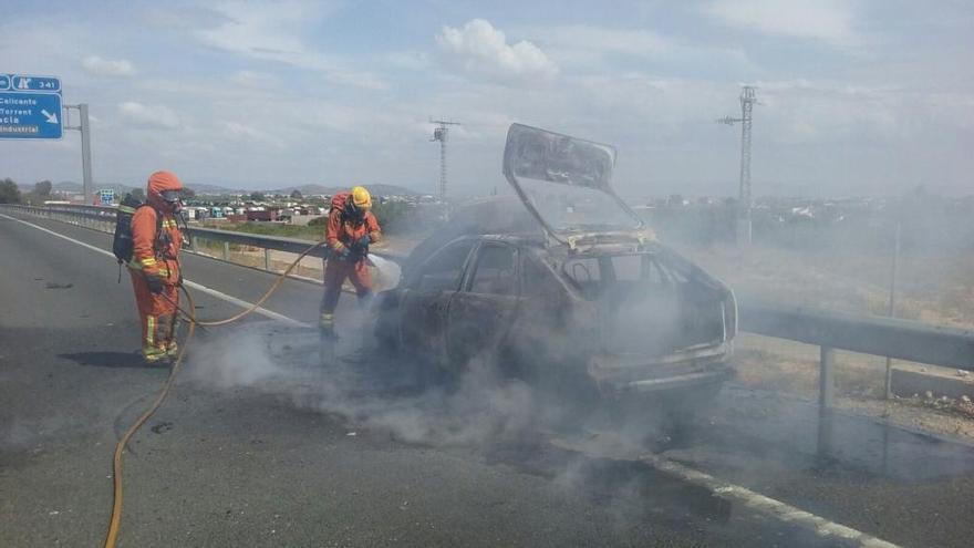 Los bomberos sofocan las llamas del coche.