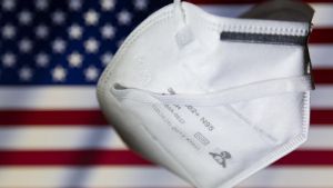 Archivo - Ilustración de una mascarilla y en el fondo la bandera de Estados Unidos