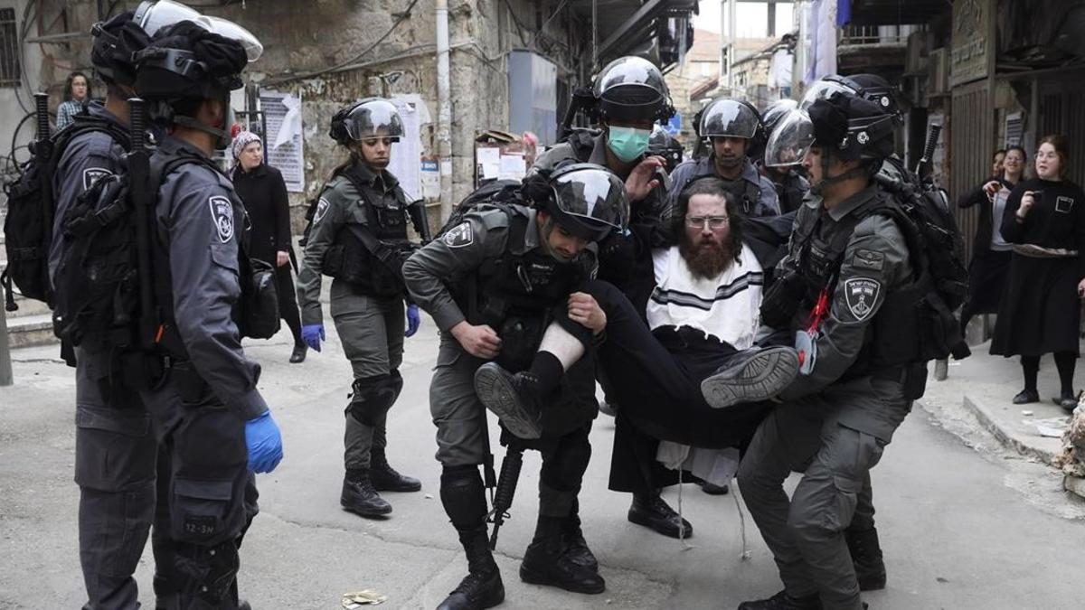 Un policía israelí detiene a un judío ultraortodoxo que protesta por las medidas de confinamiento en el barrio de Mea Shearim, en Jerusalén.