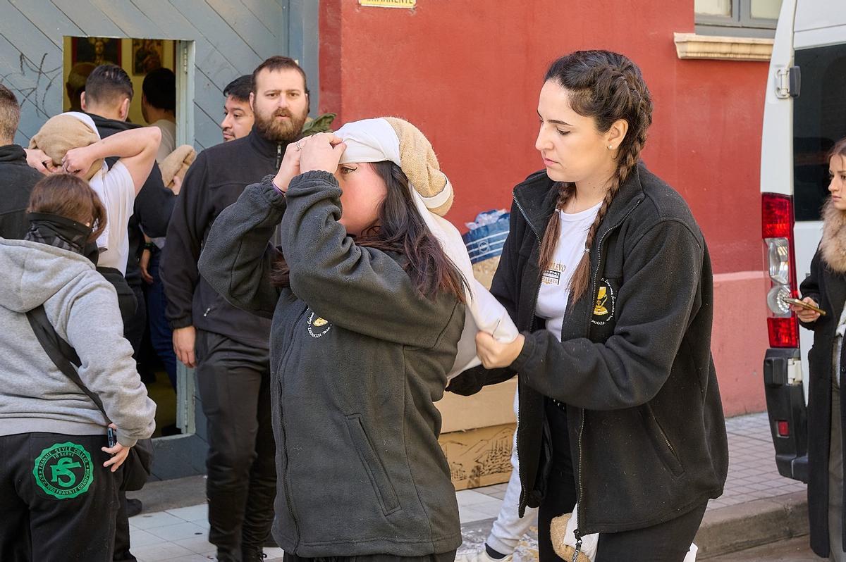 Mujeres colocándose el costal antes de meterse debajo de un paso de Semana Santa.