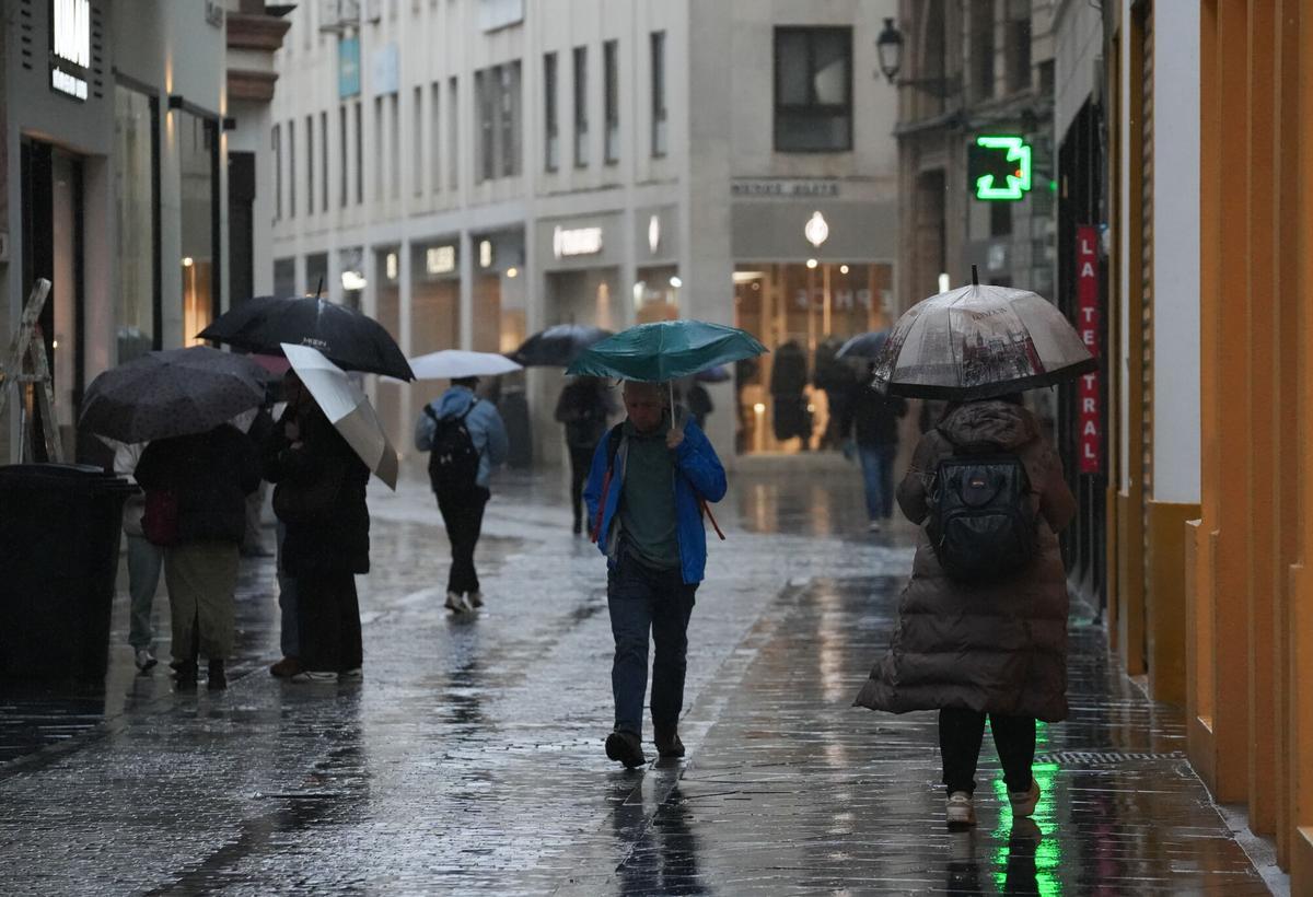 Transeúntes con paraguas en el centro de Sevilla durante el temporal de la borrasca Leonardo, que mantiene en alerta roja varios cauces de la provincia. Sevilla, España, 4 de febrero de 2026.
