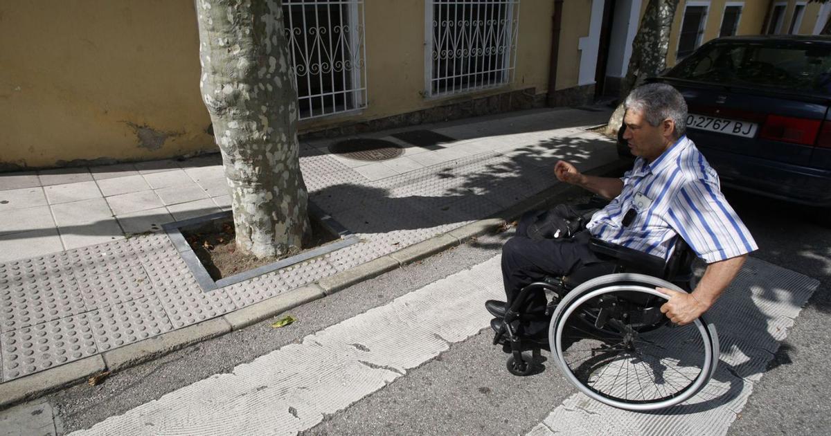 Un hombre en silla de ruedas cruza un paso de peatones del barrio del Nodo con la dificultad de tener que sortear un árbol al llegar a la acera. | Ricardo Solís
