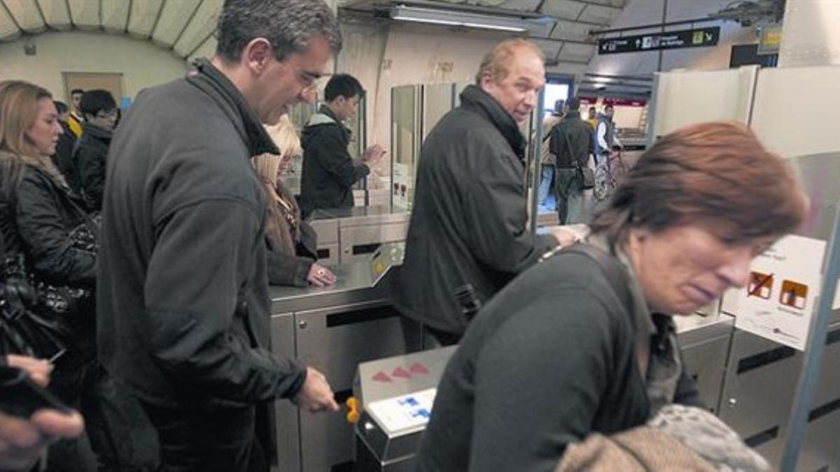 Varios usuarios validan sus billetes en la estación de metro de Plaça Espanya, ayer.