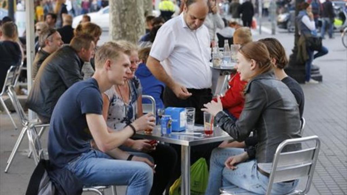 Un camarero sirve en una terraza de Barcelona.