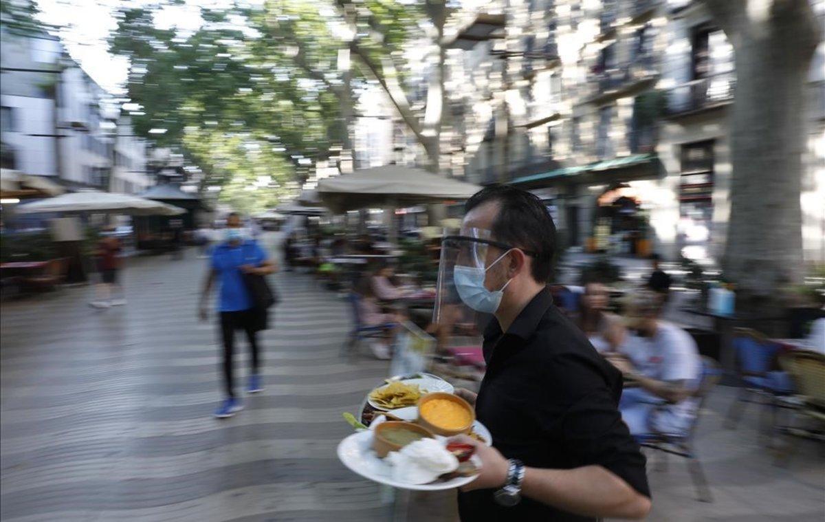 Un camarero atiende una terraza en la Rambla.