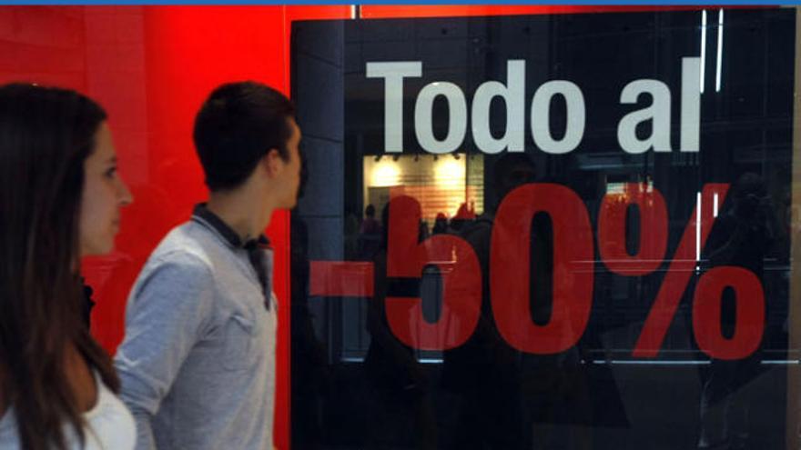 Dos jóvenes, ante un cartel de rebajas.