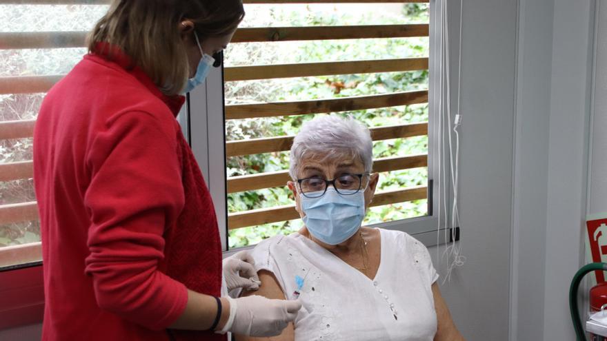 Una professional sanitària prepara el braç de la pacient abans de vacunar-la